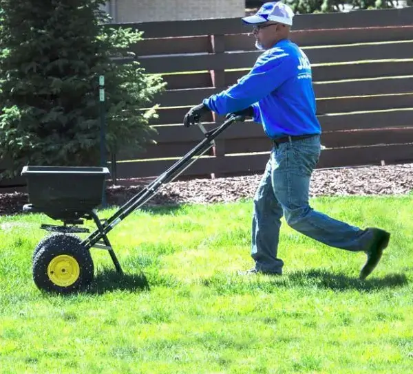 employee spreading fertilizer